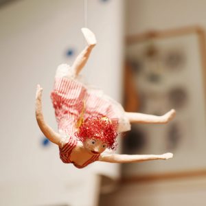 Fee Mobile in einem roten Kleid aus Pappmaché